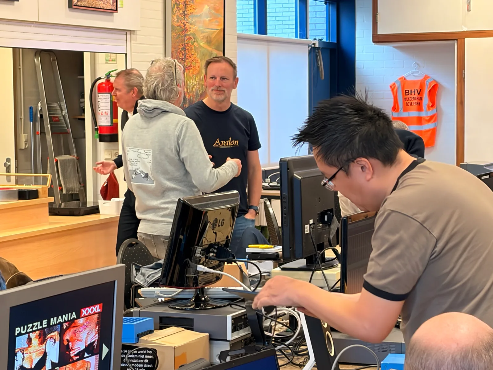 Deelnemers in gesprek tussen de opgestelde computers tijdens de MSX Meetup